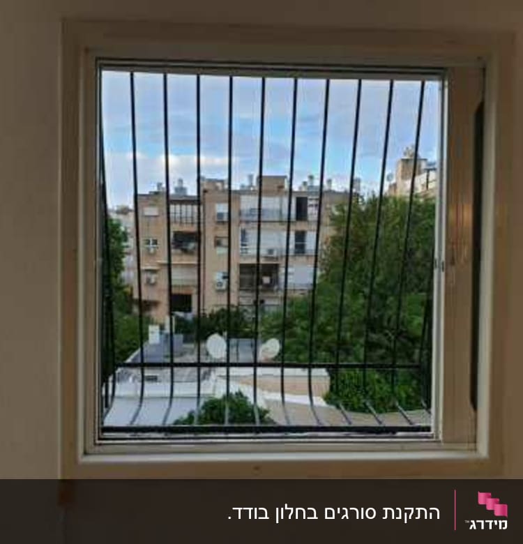 חלון עם סורגים מתכתיים מול נוף עירוני